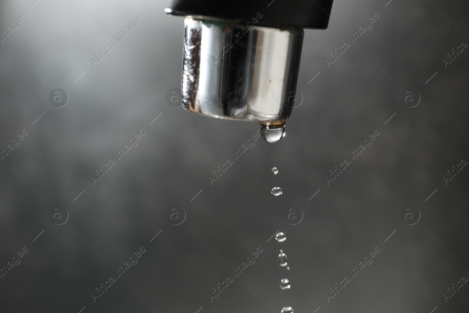 Water dripping down from faucet on grey background, closeup. Space for text Photo of Water dripping down from faucet on grey background, closeup. Space for text