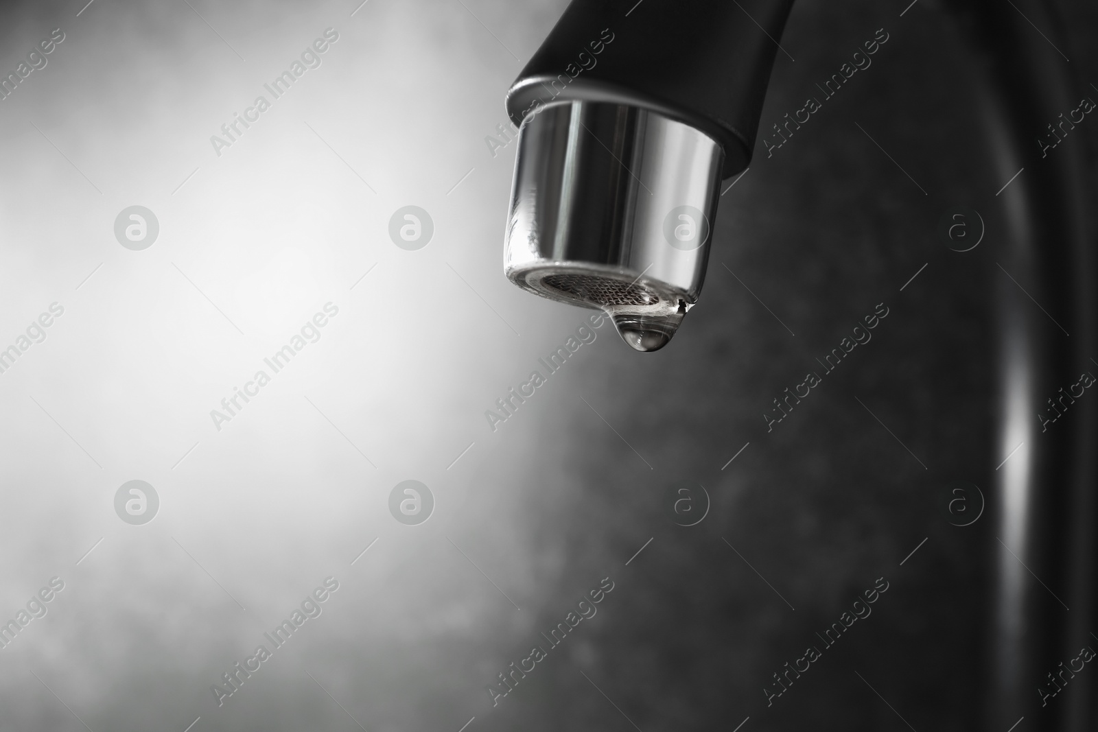 Water dripping down from faucet on grey background, closeup. Space for text Photo of Water dripping down from faucet on grey background, closeup. Space for text