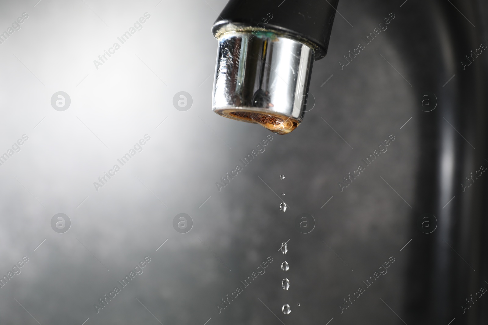 Water dripping down from faucet on grey background, closeup. Space for text Photo of Water dripping down from faucet on grey background, closeup. Space for text