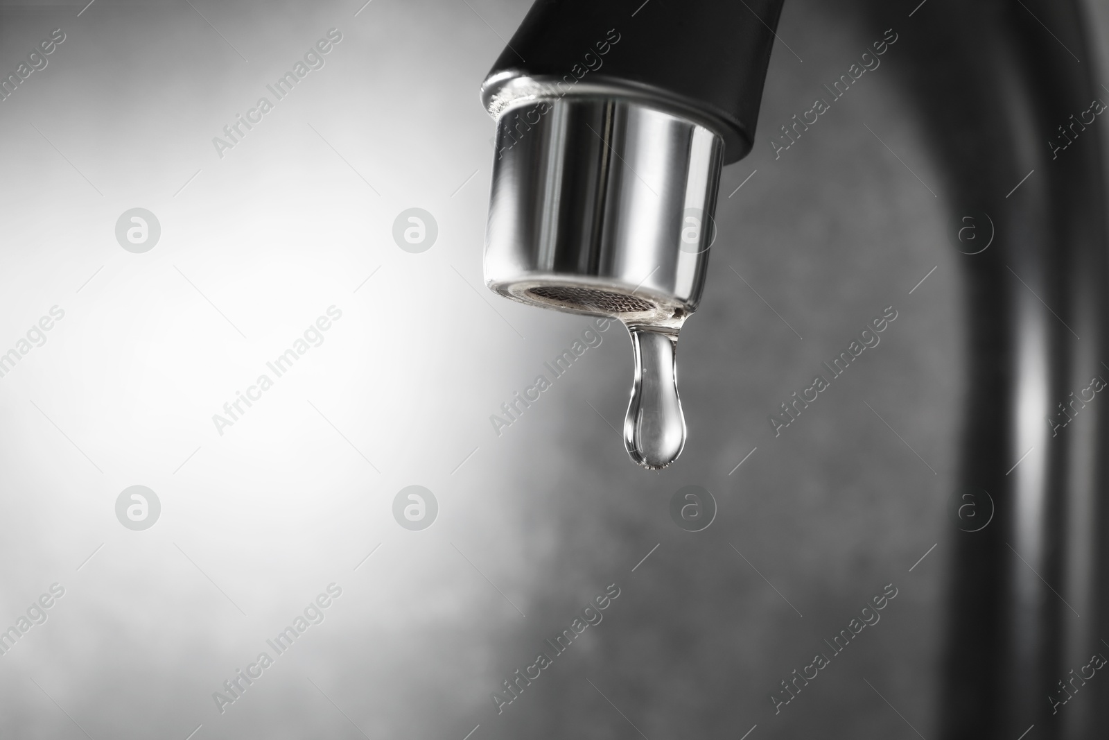 Water dripping down from faucet on grey background, closeup. Space for text Photo of Water dripping down from faucet on grey background, closeup. Space for text
