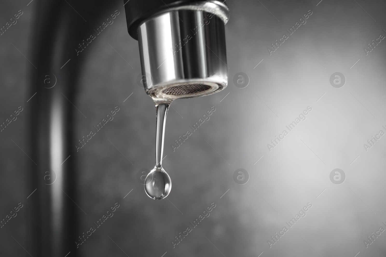 Water dripping down from faucet on grey background, closeup. Space for text Photo of Water dripping down from faucet on grey background, closeup. Space for text