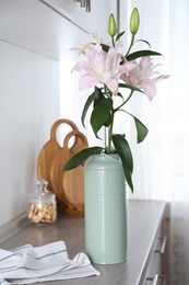 Photo of Beautiful lily flowers in can used as vase on wooden cabinet indoors