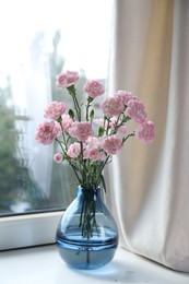 Photo of Beautiful carnation flowers in vase near window indoors