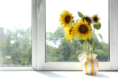 Photo of Beautiful sunflowers in jug near window indoors, space for text