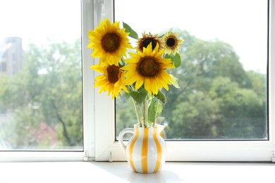 Photo of Beautiful sunflowers in jug near window indoors