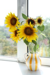 Photo of Beautiful sunflowers in jug near window indoors