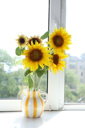 Photo of Beautiful sunflowers in jug near window indoors