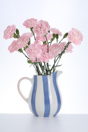 Photo of Beautiful carnation flowers in jug on white background