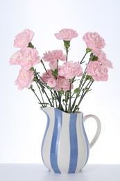 Photo of Beautiful carnation flowers in jug on white background