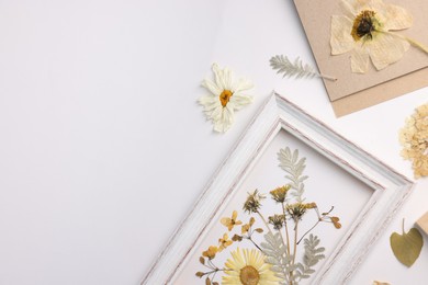 Photo of Beautiful dry flowers and green leaves in picture frame on white background, flat lay. Space for text