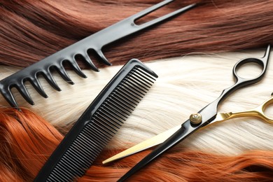 Photo of Strands of different beautiful hair, combs and hairdresser's scissors, above view