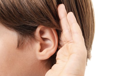 Photo of Sound. Boy showing hand to ear gesture on white background, closeup