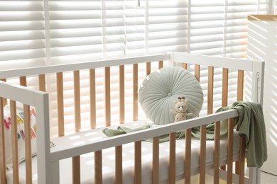 Photo of Crib with cushion, blanket and toy in baby's room
