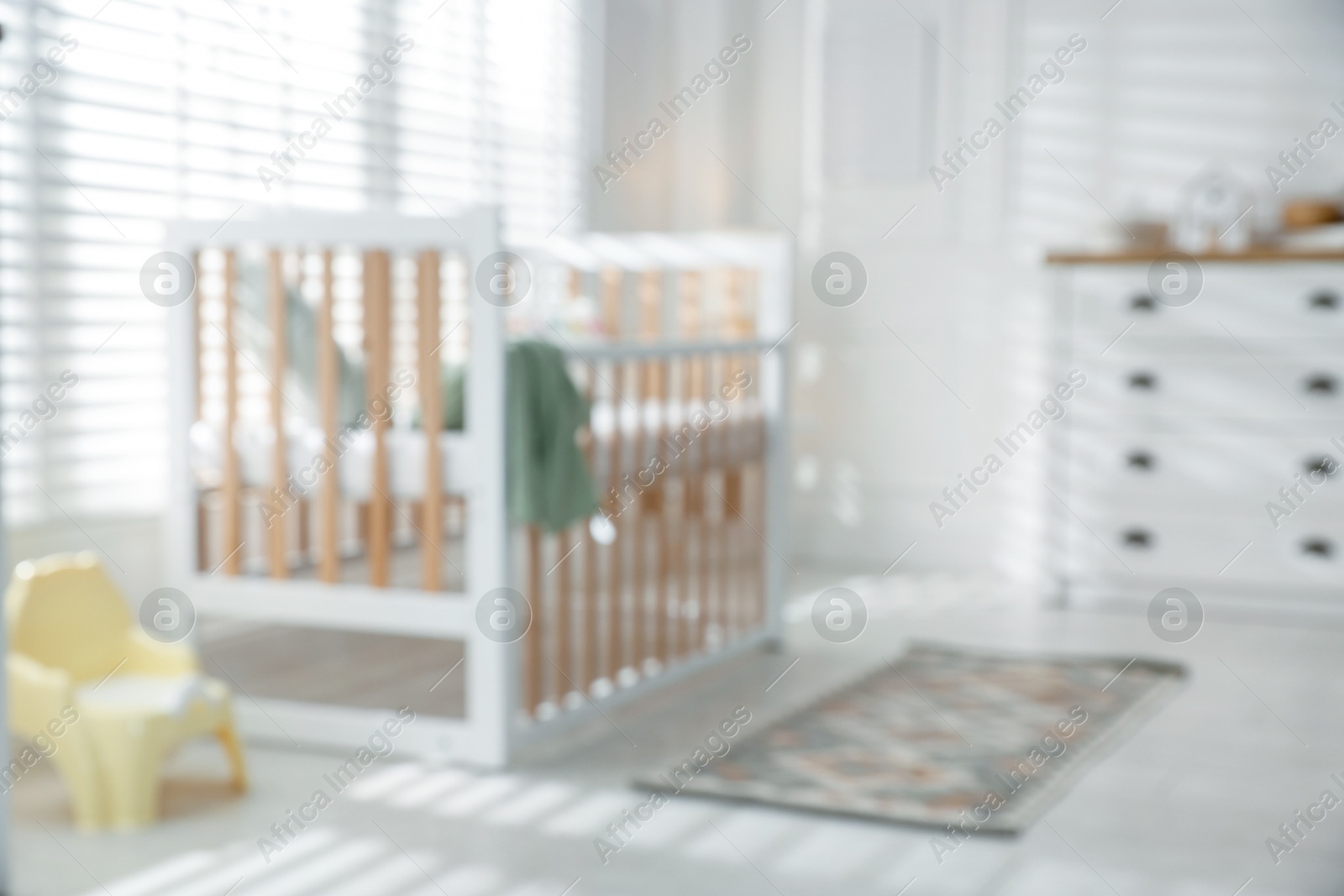 Photo of Blurred view of baby's room with stylish crib