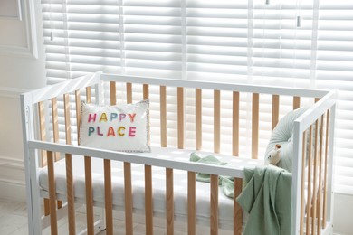 Photo of Crib with cushions, blanket and toy in baby's room