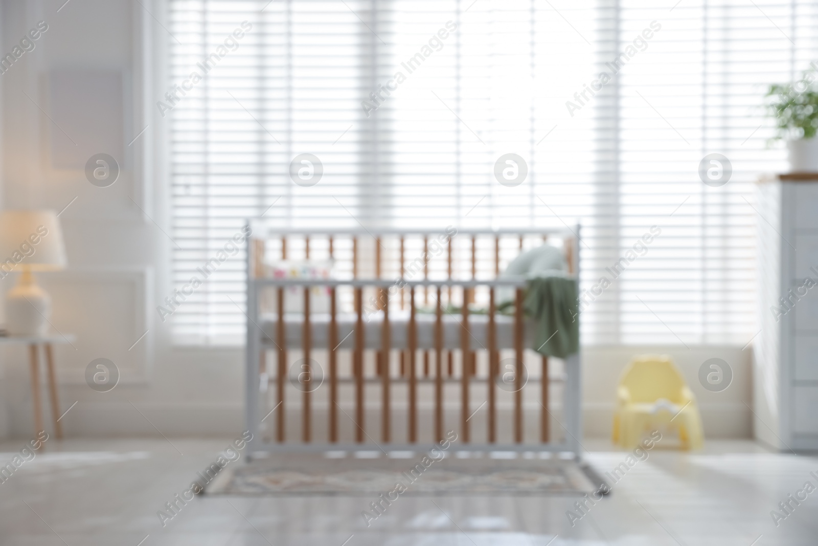 Photo of Blurred view of baby's room with stylish crib