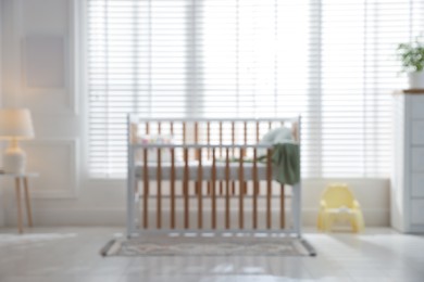 Photo of Blurred view of baby's room with stylish crib