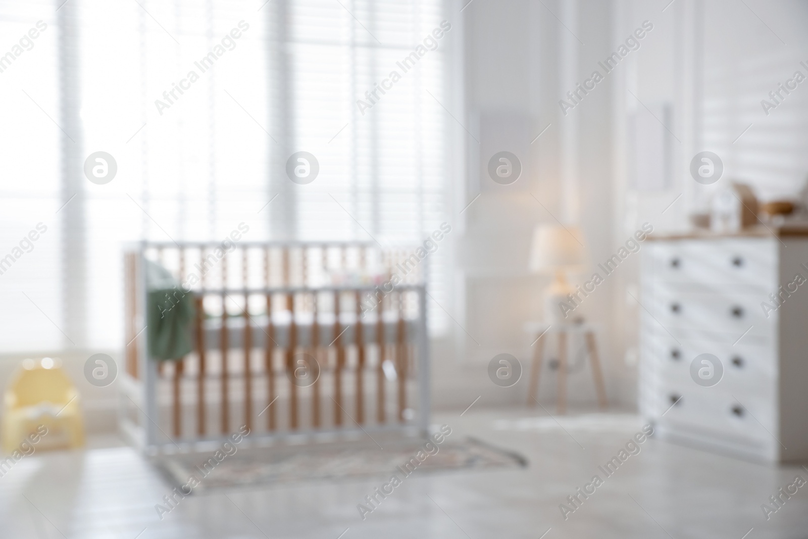 Photo of Blurred view of baby's room with stylish crib
