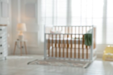 Photo of Blurred view of baby's room with stylish crib