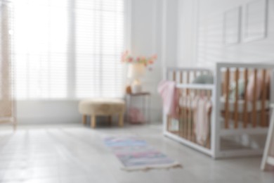 Photo of Blurred view of baby's room with stylish crib
