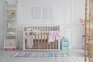 Photo of Stylish baby's room with crib and shelving unit. Interior design