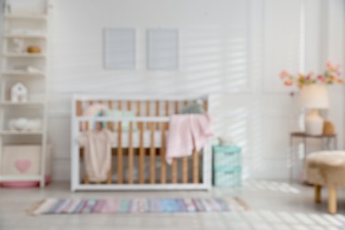 Photo of Blurred view of baby's room with stylish crib