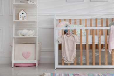 Photo of Crib with onesie and shelving unit in baby's room