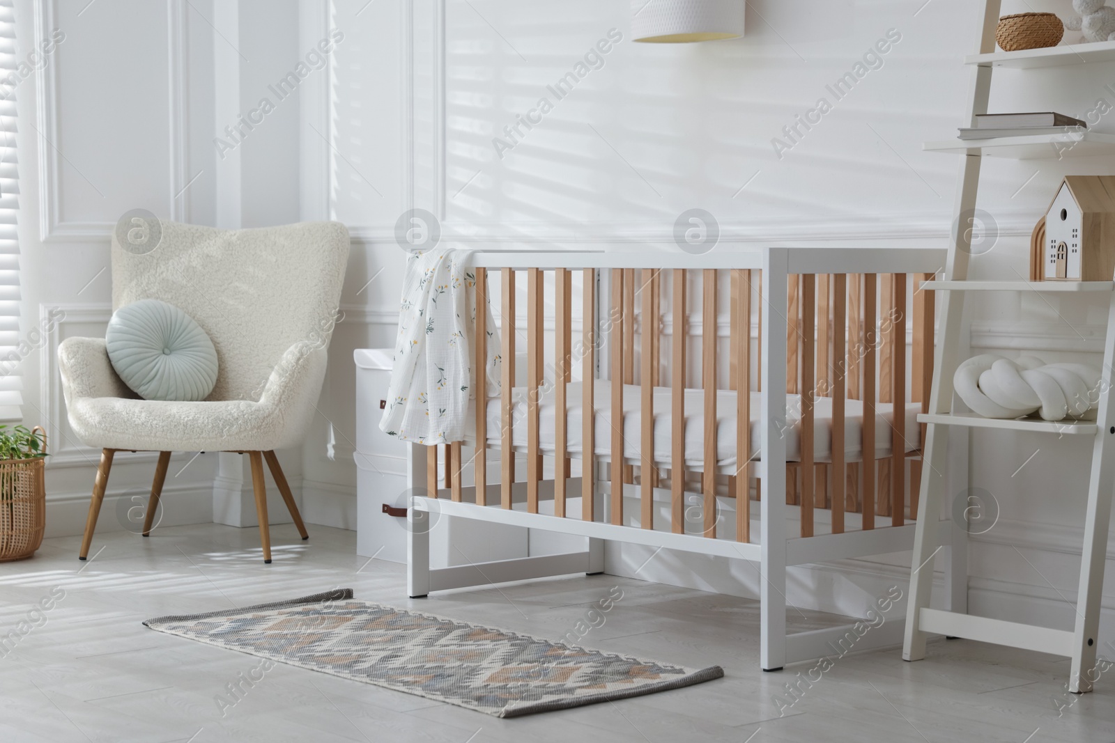 Photo of Stylish baby's room with crib and armchair. Interior design