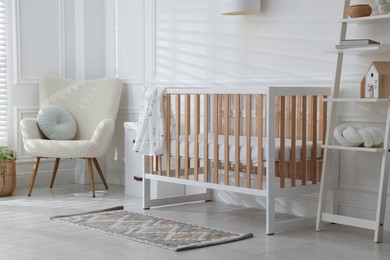 Photo of Stylish baby's room with crib and armchair. Interior design
