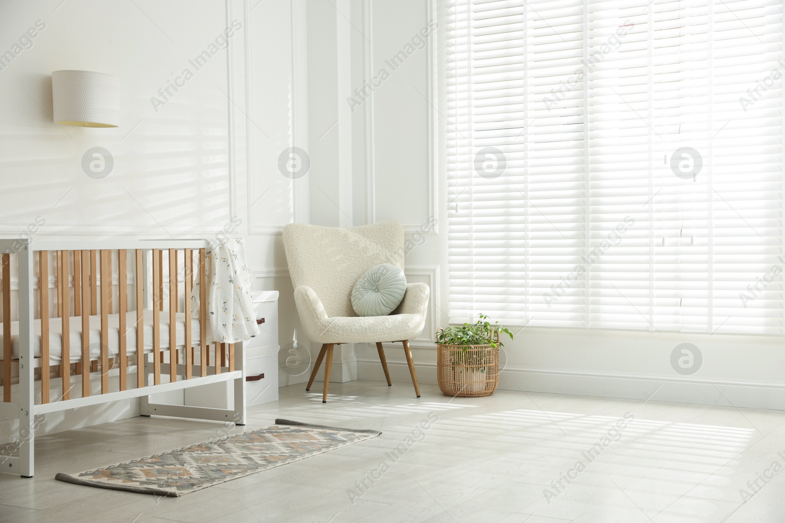 Photo of Stylish baby's room with crib and armchair. Interior design