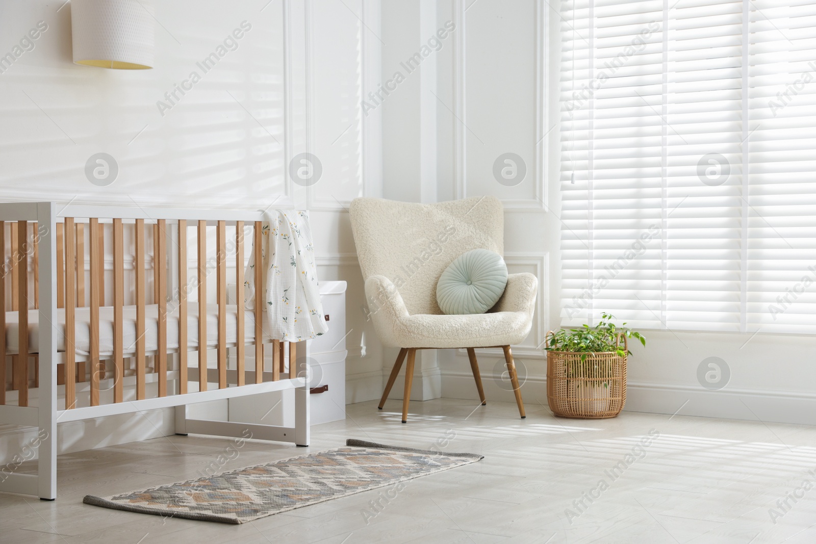 Photo of Stylish baby's room with crib and armchair. Interior design
