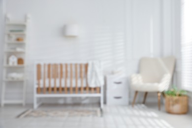 Photo of Blurred view of baby's room with stylish crib