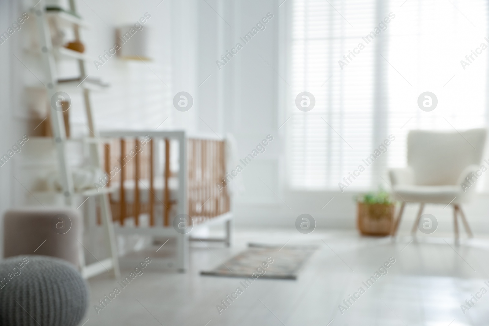 Photo of Blurred view of baby's room with stylish crib