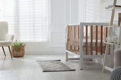 Photo of Stylish baby's room with crib and shelving unit. Interior design