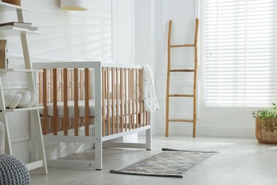 Photo of Stylish baby's room with crib and shelving unit. Interior design