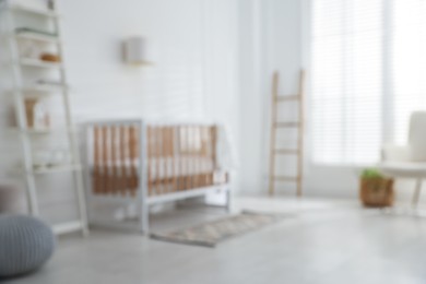 Photo of Blurred view of baby's room with stylish crib