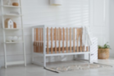 Photo of Blurred view of baby's room with stylish crib