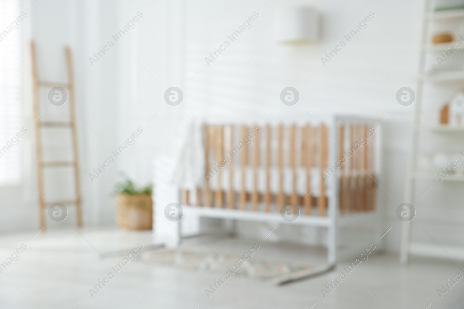 Photo of Blurred view of baby's room with stylish crib