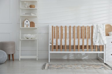 Photo of Stylish baby's room with crib and shelving unit. Interior design