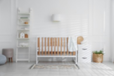 Photo of Blurred view of baby's room with stylish crib