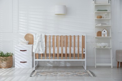 Photo of Stylish baby's room with crib and shelving unit. Interior design