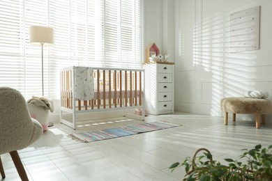 Photo of Stylish baby's room with crib and chest of drawers. Interior design
