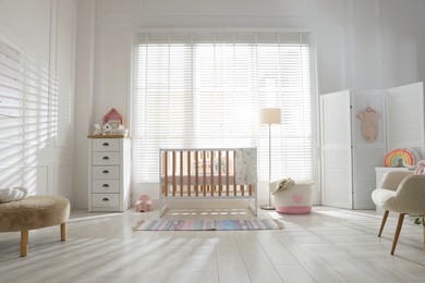 Photo of Stylish baby's room with crib and chest of drawers. Interior design