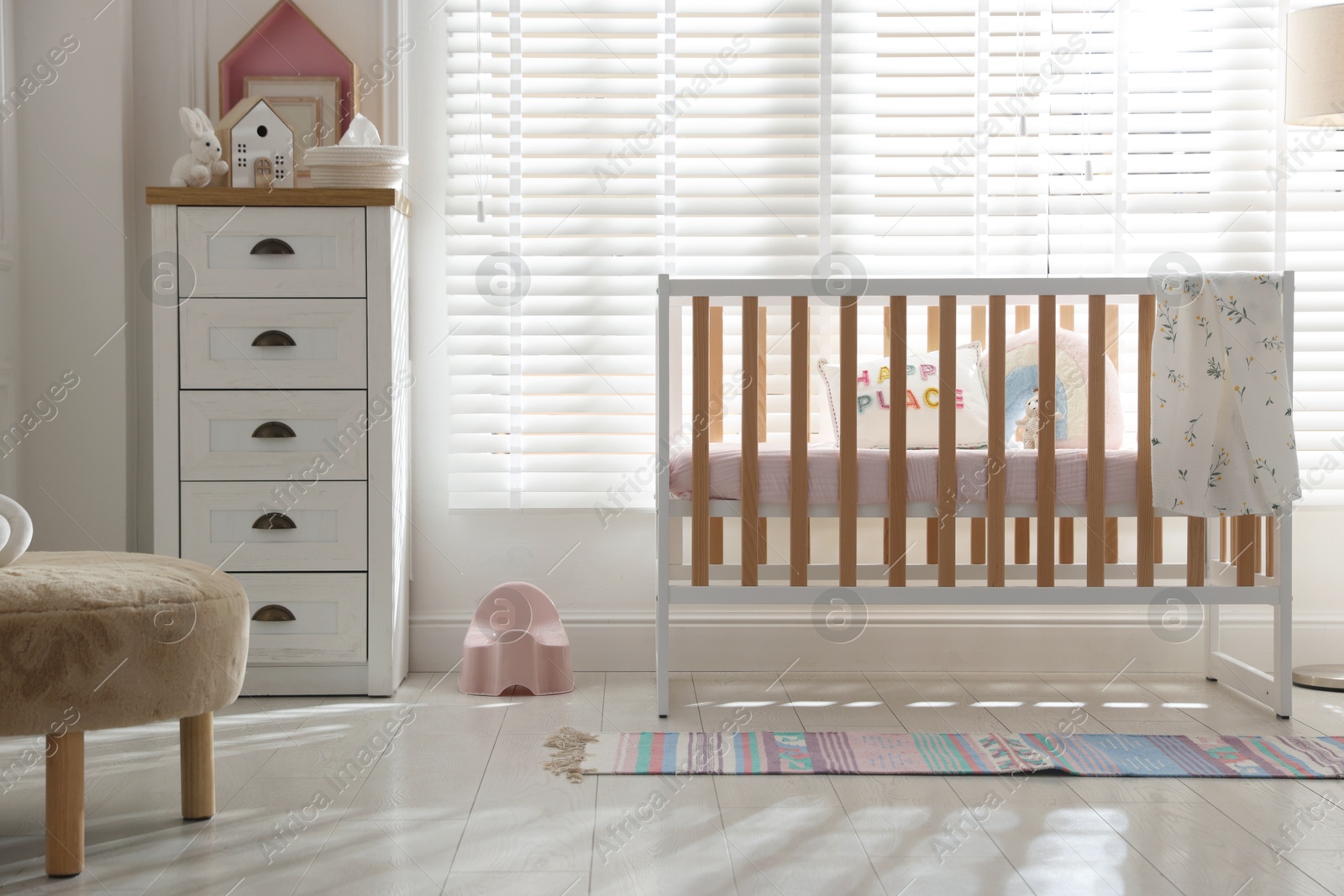 Photo of Stylish baby's room with crib and chest of drawers. Interior design