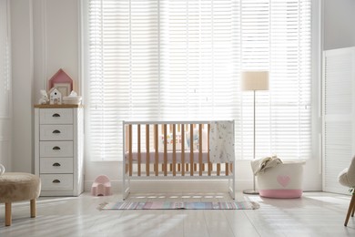Photo of Stylish baby's room with crib and chest of drawers. Interior design