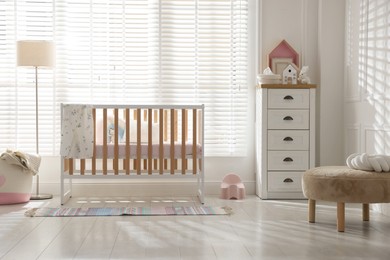 Photo of Stylish baby's room with crib and chest of drawers. Interior design