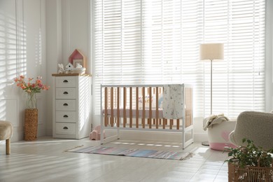 Photo of Stylish baby's room with crib and chest of drawers. Interior design