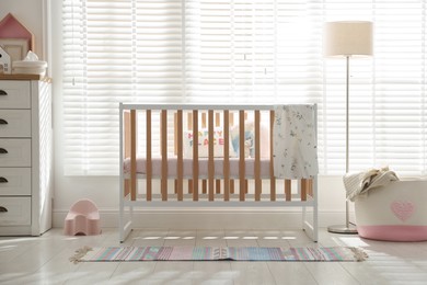 Photo of Stylish baby's room with crib and chest of drawers. Interior design