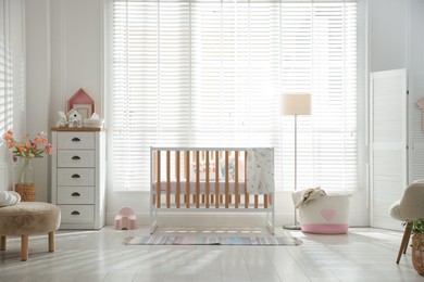Photo of Stylish baby's room with crib and chest of drawers. Interior design