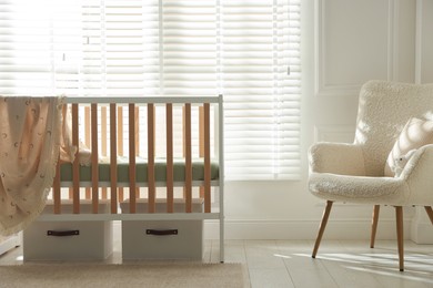 Photo of Stylish baby's room with crib and armchair. Interior design